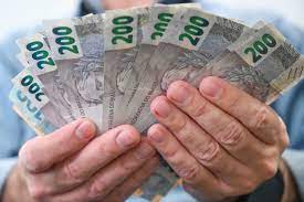 mão de uma pessoa segurando notas de 200 reais