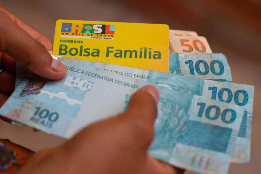 maos segurando cartão do bolsa familia e dinheiro