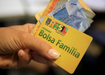 mãos segurando direito e o cartão do Bolsa Família 2024
