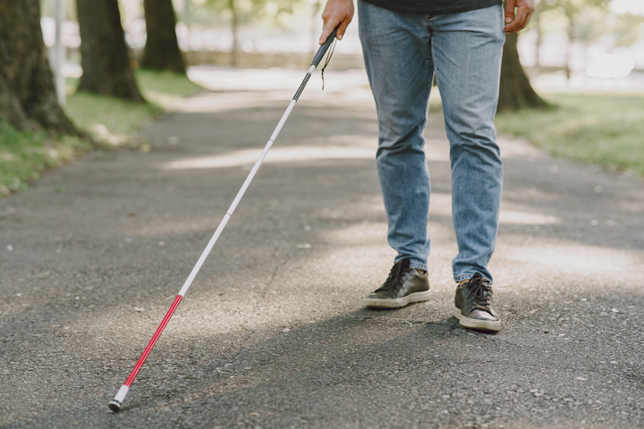 homem andando com a bengala que indica a sua deficiência visual para falar sobre a aposentadoria por invalidez.