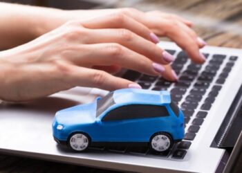 imagem de uma pessoa no notebook com uma miniatura de carro para solicitar o IPVA devolvido