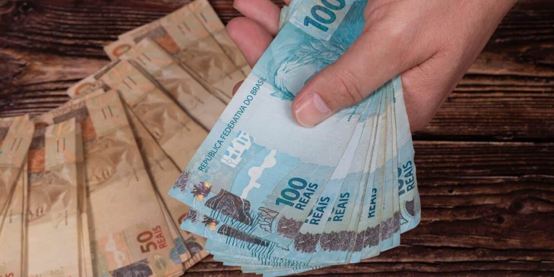 imagem de uma mão com notas de dinheiro do pagamento do 13º INSS