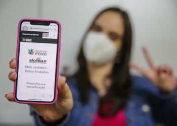 imagem com uma mulher segurando um celular com o app do Bolsa Trabalho