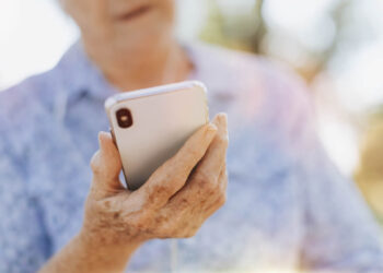 imagem de uma senhora segurando uma celular para fazer a prova de vida inss